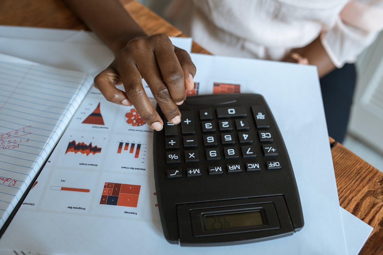 Person at desk with calculator and financial charts for value-based pricing analysis
