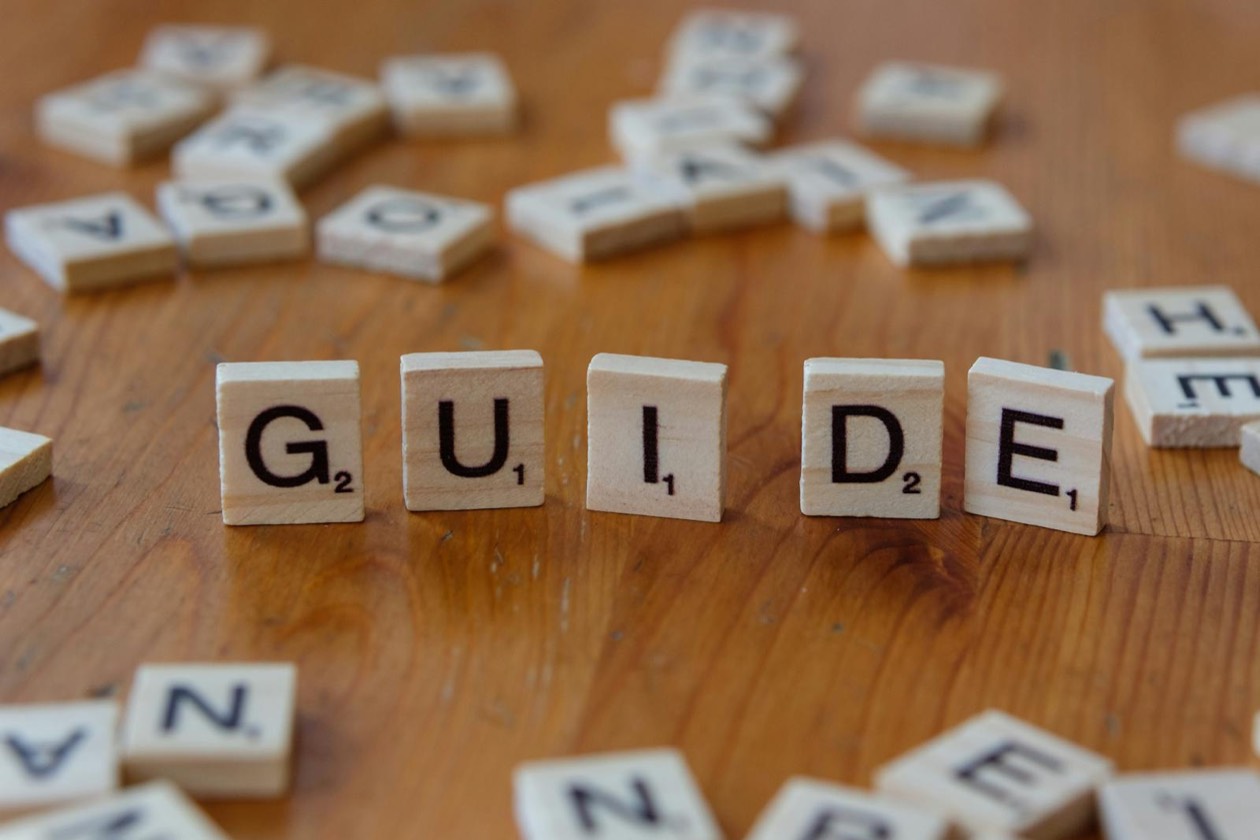Wooden letter tiles spelling the word Guide &mdash; familiar words and cognitive fluency in copywriting